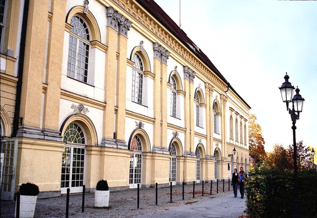 A long yellow palace front with tall arched windows along a street.