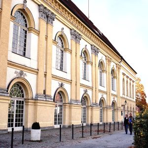 A long yellow palace front with tall arched windows along a street.
