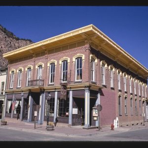 A two-story red-brick building with arched window hoods and a very deep cornice, a restaurant sign hanging at the corner.