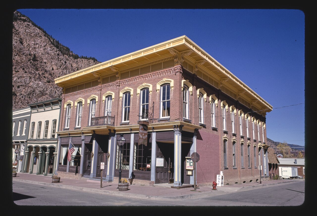 A two-story red-brick building with arched window hoods and a very deep cornice, a restaurant sign hanging at the corner.