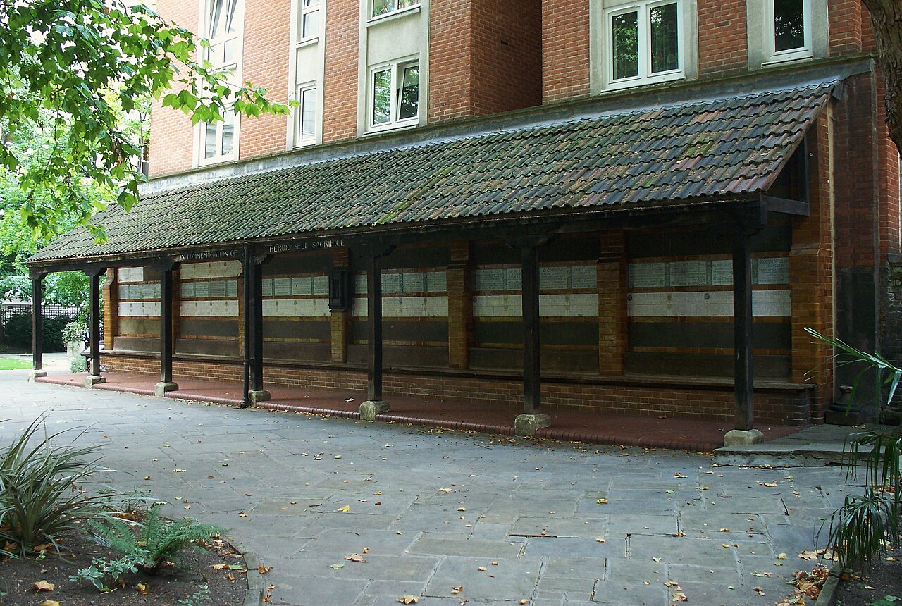 A long timber shelter with a tiled roof over a brick wall set with rows of white ceramic tablets.