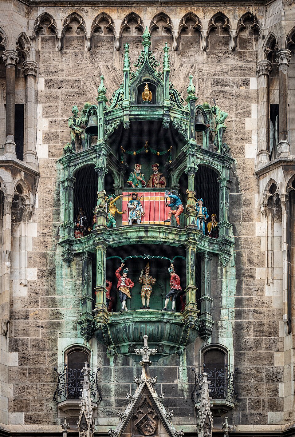 A green copper bay of two open tiers with small costumed figures.
