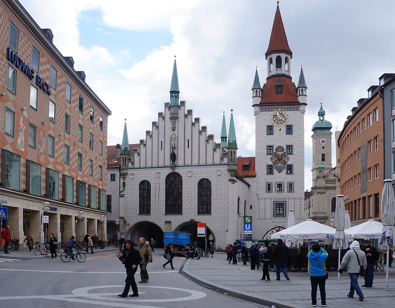 A white Gothic hall with a stepped gable and a tall clock tower with a red spire.