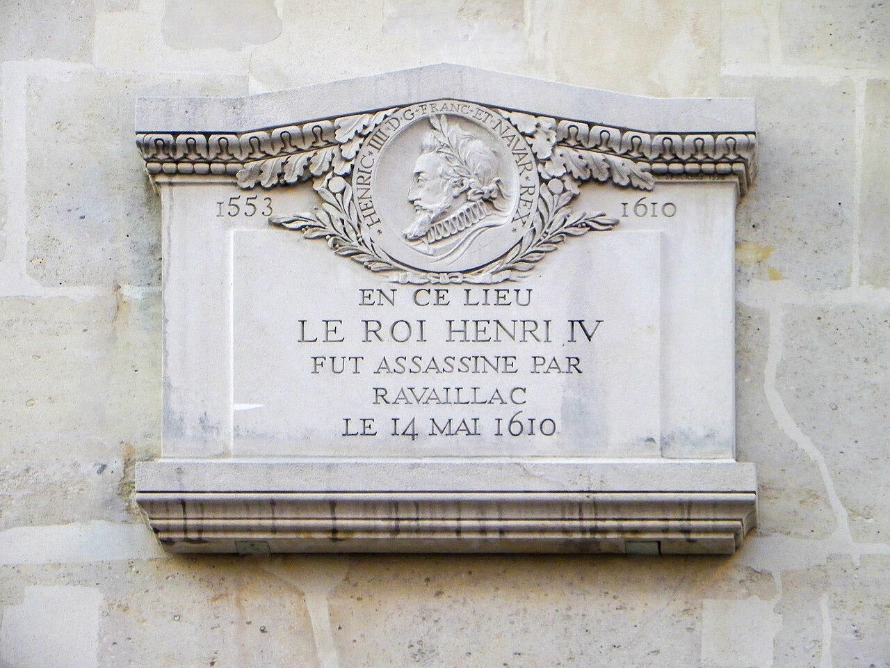 A white stone plaque with a portrait medallion, the dates 1553 and 1610 and an inscription in capitals.