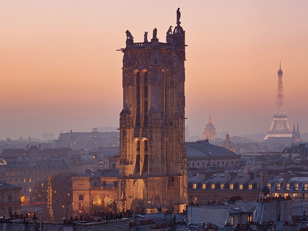 The Tour Saint-Jacques at dusk, a tall Flamboyant Gothic tower with statues at its top corners.