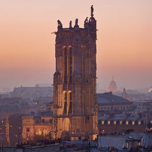 The Tour Saint-Jacques at dusk, a tall Flamboyant Gothic tower with statues at its top corners.