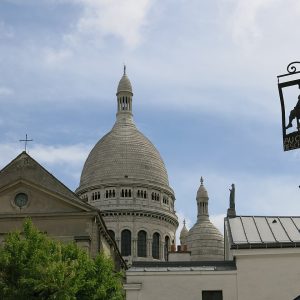 A plain church gable with a round window in front of a large white dome.
