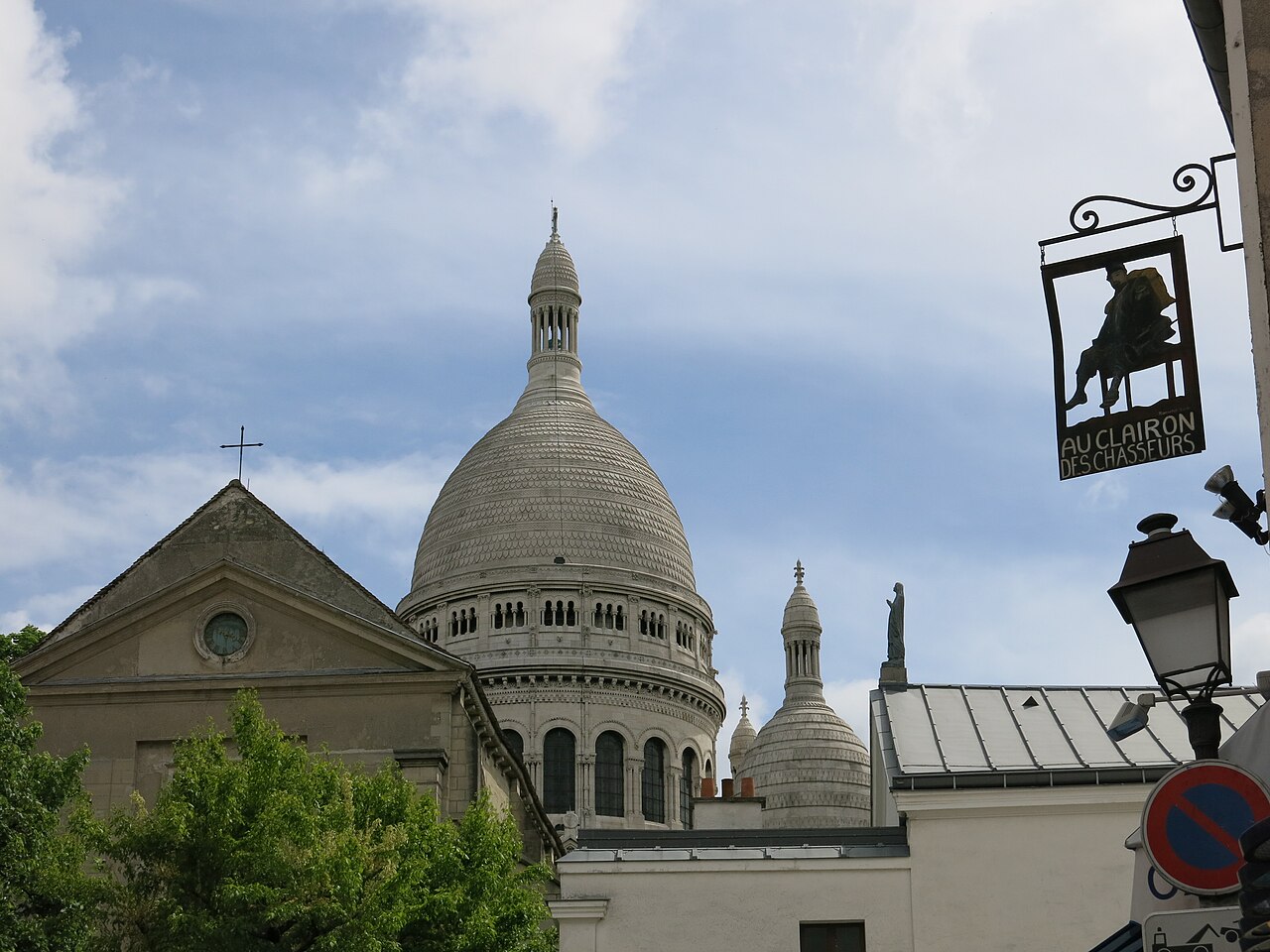 A plain church gable with a round window in front of a large white dome.