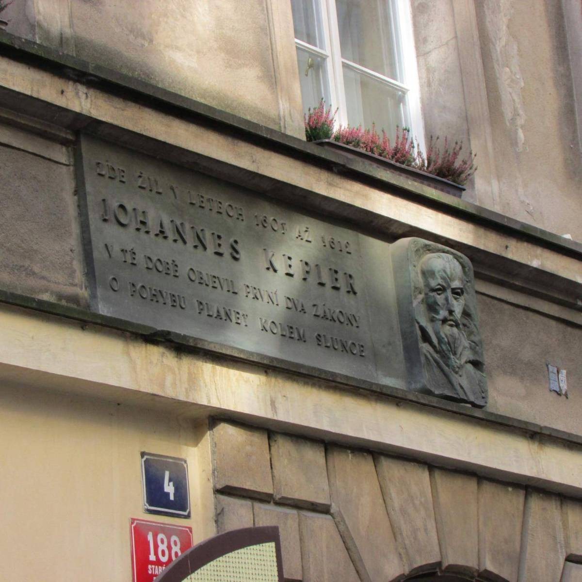A large bronze plaque with raised Czech lettering and a relief portrait, above the house number 4.