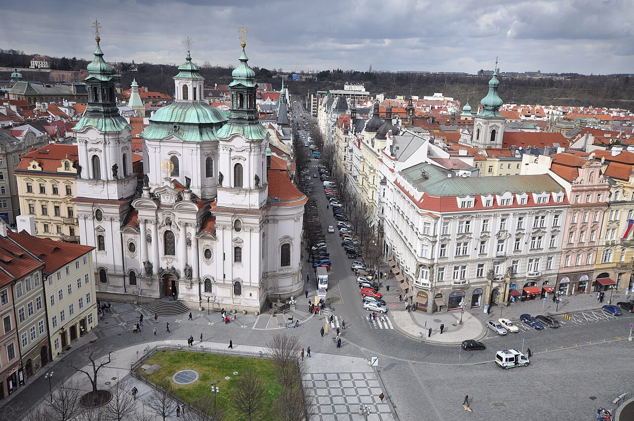 Aerial view of a straight avenue lined with large apartment blocks, a domed church at left.