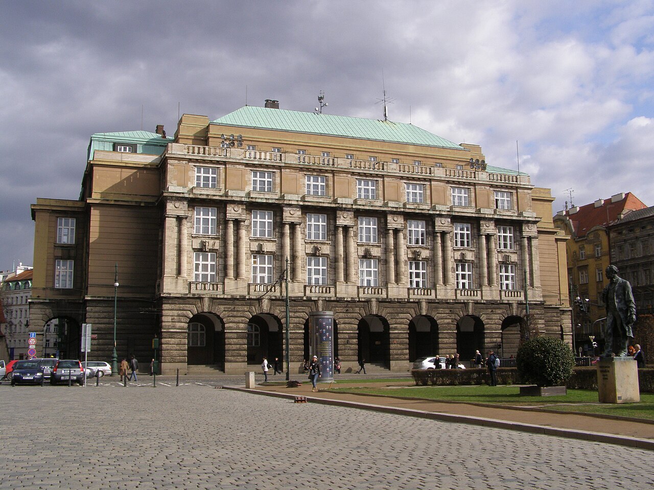 A large stone university building with an arcaded ground floor on a city square.