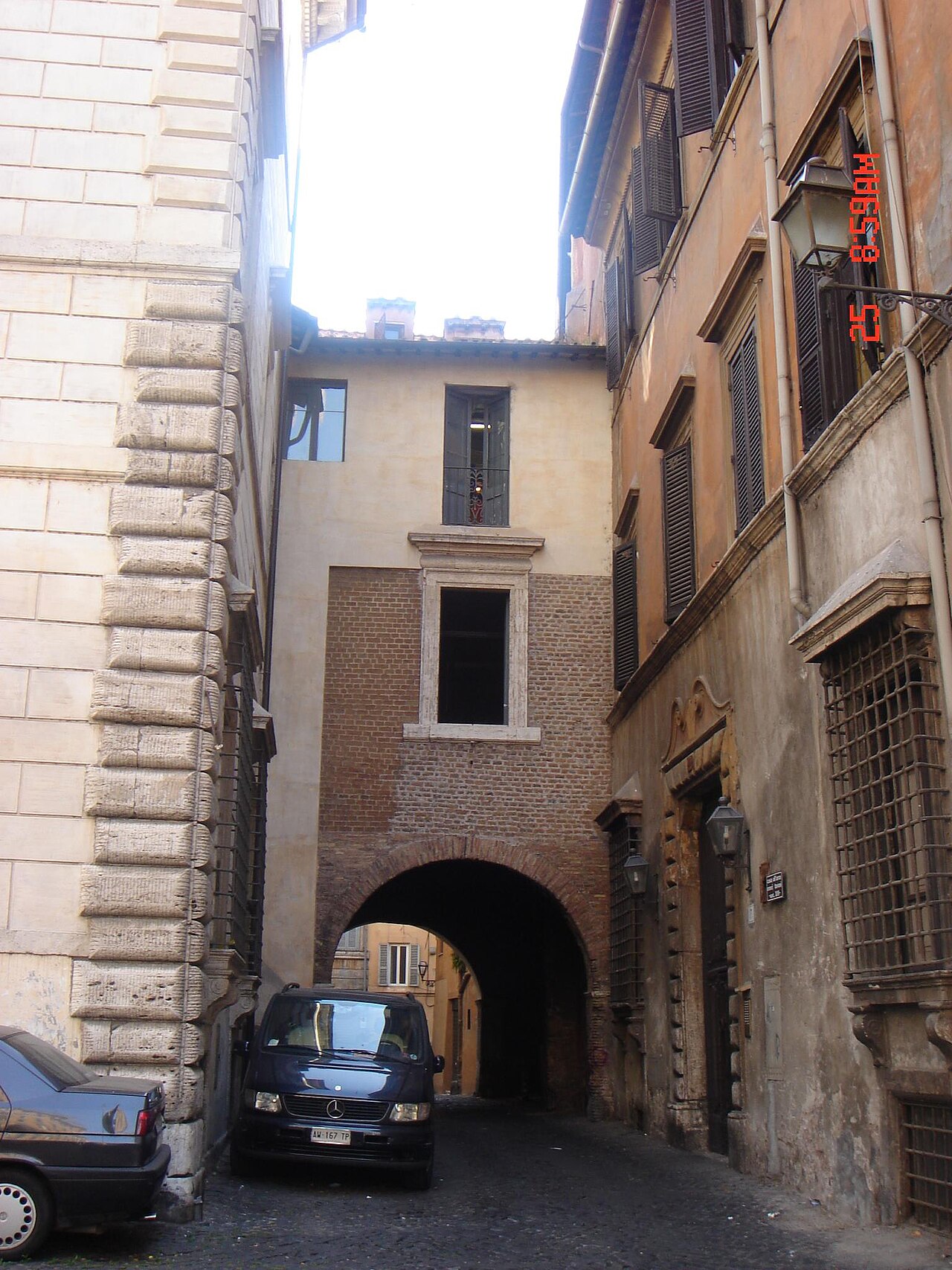A low arch through a building leading into a narrow lane.