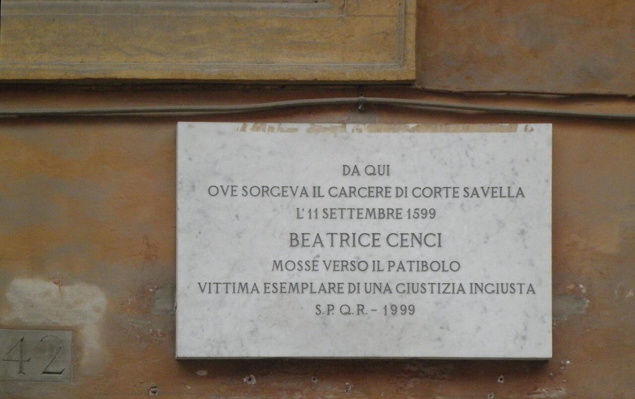 A marble plaque on a wall with an inscription in capital letters.