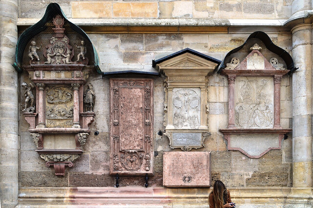 Carved stone plaques of different sizes set into a weathered stone wall.
