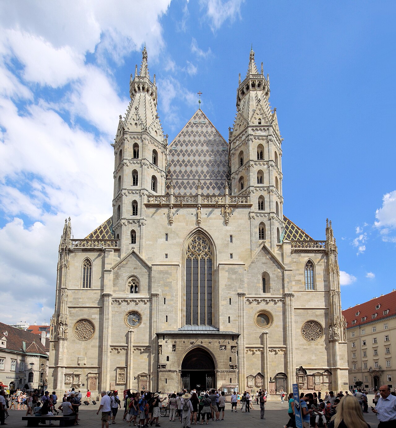 A Romanesque stone front with a deep round-arched portal between two slender octagonal towers, a tall Gothic roof behind.
